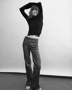 a black and white photo of a woman with her hands on her head wearing jeans