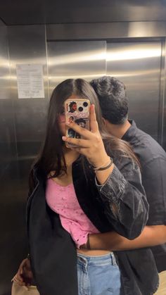 a woman taking a selfie with her cell phone in front of an elevator door