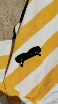 a pair of black high heeled shoes laying on a yellow and white striped towel