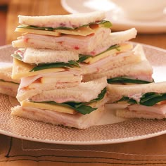 a stack of sandwiches sitting on top of a plate next to a cup and saucer