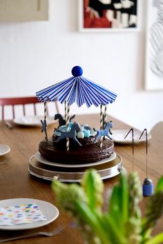 a chocolate cake with an umbrella decoration on top is sitting on a table in front of plates