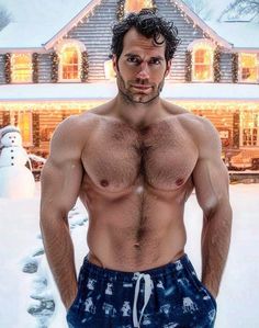 a shirtless man standing in front of a snow covered house with his hands on his hips