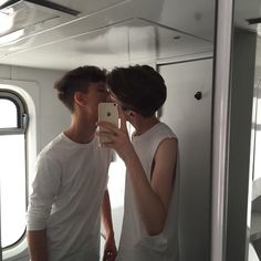 two people taking a selfie in front of a mirror with their cell phone up to their ear