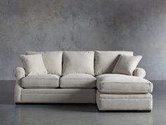 a white couch sitting in front of a gray wall with pillows on top of it