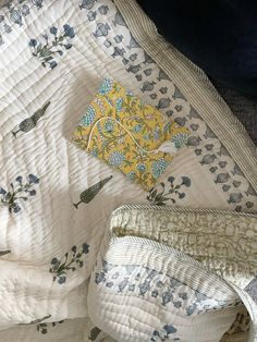 a quilted bed with blue and yellow designs on the cover, next to a pillow