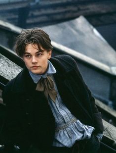 a young man sitting on top of a wooden bench