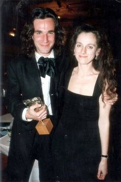 a man in a tuxedo standing next to a woman wearing a black dress