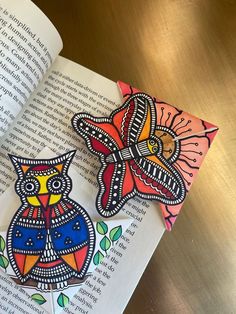 an open book sitting on top of a wooden table next to two paper cut outs