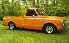 an orange pickup truck parked in the grass