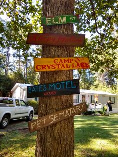 a tree with several signs on it in front of a camper and rv park