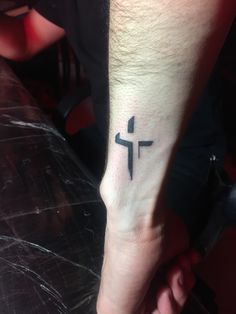 a small cross tattoo on the foot of a person's left foot, which is black and white