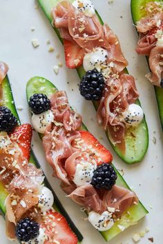 cucumbers with blackberries, strawberries and prosciutto on them