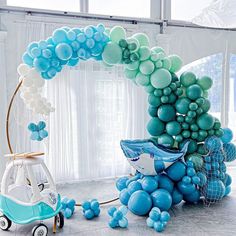 a blue and white balloon arch next to a scooter with balloons on it