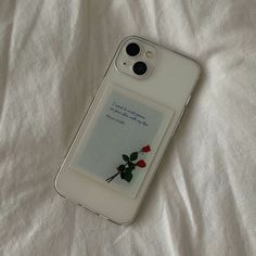 an iphone case with a card attached to it sitting on a white sheeted surface