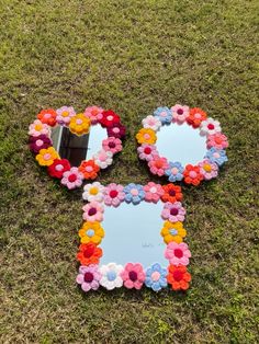 three flower shaped mirrors sitting on top of a grass covered field next to a mirror