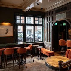 the interior of a restaurant with orange chairs and wooden tables in front of large windows