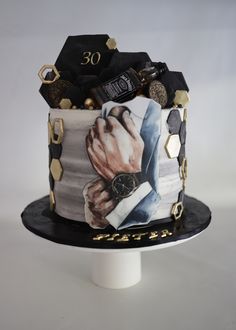 a black and white cake with gold decorations on it's sides, decorated with a photo of a man holding his hand