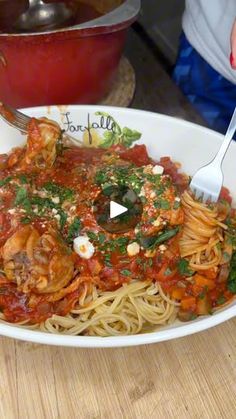 a plate of pasta with shrimp and tomato sauce on it, being held by a fork