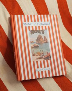 an orange and white striped blanket on top of a bed next to a small book