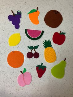 an assortment of felt fruits and vegetables on a white countertop with grey speckles