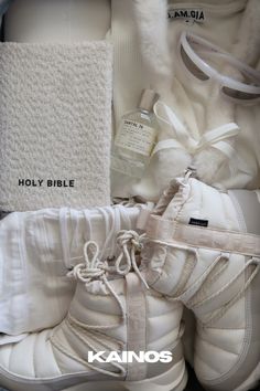 a pair of white snow boots sitting on top of a pile of clothing