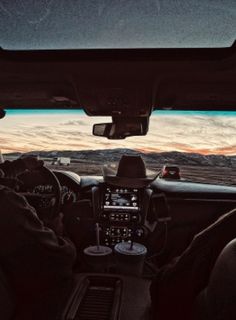 two men in the back seat of a car driving down a road at sunset or dawn