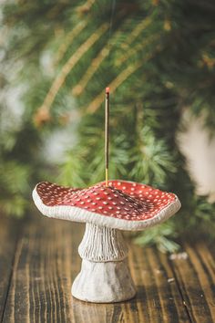 a red and white polka dot umbrella sitting on top of a table next to a pine tree