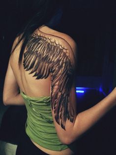 the back of a woman's shoulder with an angel wing tattoo on her arm