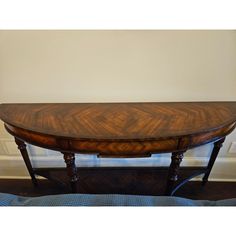 a wooden table sitting on top of a hard wood floor next to a white wall