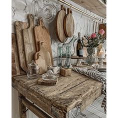 an old wooden table topped with cutting boards and other kitchen utensils on top of it