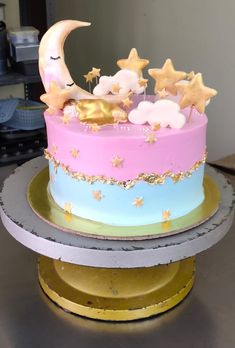 a cake decorated with stars, moon and clouds on top of a gold plated stand