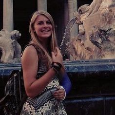 a woman is standing in front of a fountain