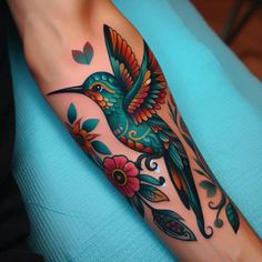 a colorful bird with flowers on it's arm is shown in this tattoo design