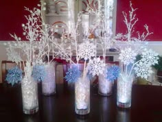 four vases with snowflakes in them sitting on a table