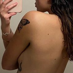 a woman taking a selfie with her cell phone in front of her face and butterfly tattoo on her back