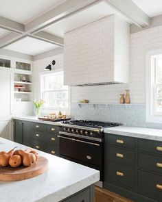 a kitchen with green cabinets and white counter tops, an oven and stove top in the center