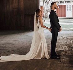 a bride and groom standing in an old barn looking into each other's eyes