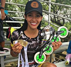 a woman sitting on a bench holding up her skateboard and two gold medal medals