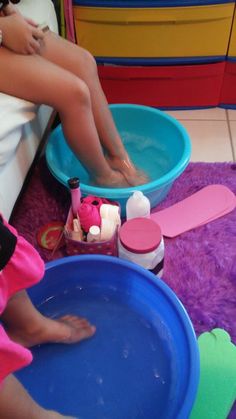 a child's feet in a blue bowl on the floor next to other children's toys