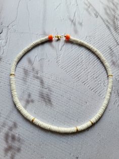 The necklace is made of heishi shell beads in white, with gold & neon orange accents. Modern design that can be easily combined or is also an eye-catcher on its own. The clasp and other metal components are high-quality gold-plated. The diameter of the disc beads is: 6 mm Choose your perfect length: 42cm or 45cm --------------------------------- Materials used: Heishi beads made of shells (white), gold-plated disc beads & gold-plated snap clasp, polymer clay disc beads (neon yellow) Handmade White Heishi Beads Choker, White Spacer Beads Jewelry For Summer, White Heishi Beads Necklace For Beach, White Single Strand Minimalist Jewelry, Minimalist White Beaded Necklaces For Beach, Minimalist White Beaded Necklaces For Summer, Trendy White Single Strand Beaded Necklace, Minimalist White Beaded Necklace For The Beach, Minimalist White Beaded Necklace For Beach