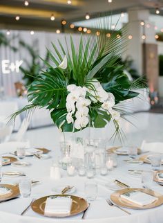 a white table topped with lots of plates and vases filled with flowers next to candles