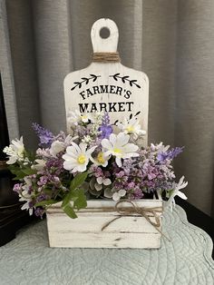 a wooden box filled with flowers sitting on top of a white table covered in a sign