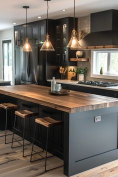 a kitchen with black cabinets and wooden counter tops, lights hanging from the ceiling over the island