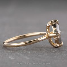 a yellow gold engagement ring with a square cut diamond in the center, on a gray surface