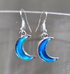 "One of a kind hand painted (blue alcohol ink) and resin (white and clear, creates a glass like finish) blue moon earrings. Hung on sterling silver French ear wires. This lightweight design is approximately 1.25\" length. Be like the moon. The moon reminds us to see beauty in darkness.  Her glow takes many shapes, embracing individuality and change. She is beautiful in all forms. She is unique, authentic and true. Photos taken in studio light Free U.S. shipping. International shipping available. Same item as shown, contact me for free sizing adjustments. Shipped in a sealed and protected plastic bag. Gift wrap and gift card available. Price for gift wrap contingent upon your request. Free customer consultation offered to create a client profile I keep on hand with measurements and preferen Silver Round Resin Earrings, Blue Enamel Dangle Jewelry, Blue Crescent Moon Charm Earrings, Blue Moon-shaped Earrings With Moon Charm, Blue Moon-shaped Metal Jewelry, Blue Moon Shaped Earrings With Moon Charm, Blue Dangle Earrings With Moon Charm, Blue Round Earrings With Moon Charm, Nickel-free Blue Enamel Jewelry