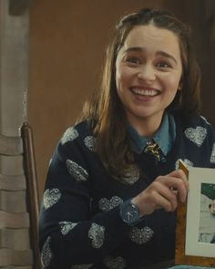 a woman sitting at a table holding up a photo