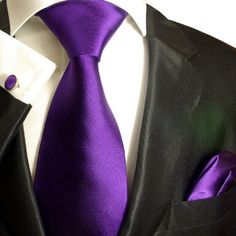 a man wearing a black suit with a purple tie and pocket square handkerchief on his lapel