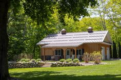 a small house sitting in the middle of a lush green field with lots of trees