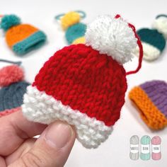 a hand holding a small knitted hat in front of other crocheted hats