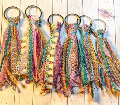 four different colored ties hanging from metal rings on a wooden floor with white boards in the background